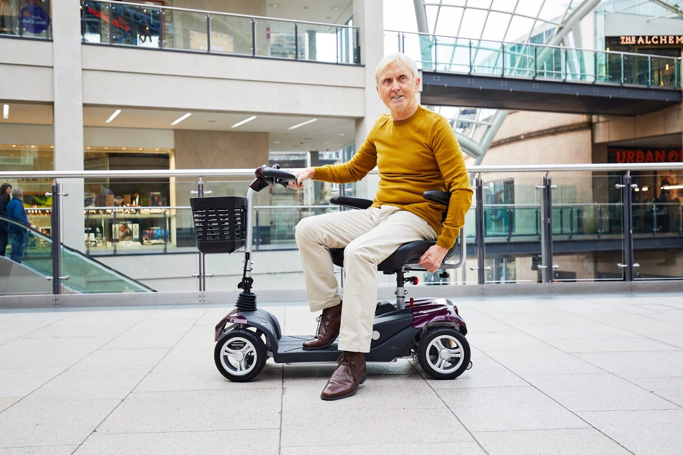 Showing a man sat on the Airium using the swivel seat in a shopping centre